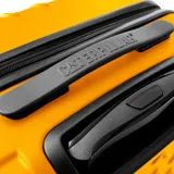 Maleta rígida con ruedas, color amarillo, con diseño texturizado en forma de rombos. Tiene manija retráctil, candado de seguridad y logo de la marca.