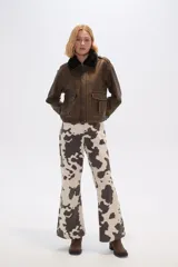 Campera marrón de eco-cuero con cuello de piel sintética negra, cierre frontal con botones a presión, bolsillos con solapa en el pecho y corte holgado.