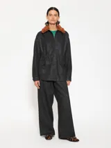 Parka negra de gabardina con cuello desmontable de peluche color marrón, bolsillos delanteros y cintura ajustable.