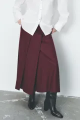 Falda midi color borgoña de tiro alto con tablas en el delantero y cierre frontal cruzado con botones a presión.