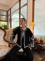 Campera blanca de algodón con bordados florales en color crema, corte recto y mangas acampanadas.