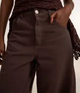 Pantalón barrel de cintura alta color marrón, confeccionado en sarga de algodón certificado BCI, con trabillas en la cintura, cierre tradicional, bolsillos convencionales y bolsillo reloj.