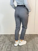 Pantalón gris con estampado de espiga, corte recto, cintura elastizada con lazo negro y bolsillos laterales.