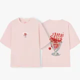 Remera rosa de corte holgado con estampado de cerezas y texto en la espalda.