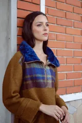 Buzo de lana color beige con cuello alto con cierre y aplique de corderito en el cuello. De mangas rectas y corte amplio.