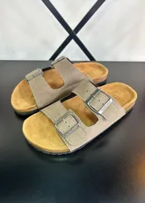 Sandalias de dedo color beige con doble tira y hebillas metálicas.