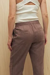 Pantalón beige de tiro medio con cintura elastizada y cordón regulable, bolsillos laterales y calce relajado.