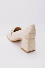 Zapato de cuero color beige con textura croco, taco cuadrado y detalle de apliques dorados.