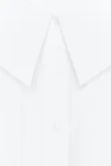 Camisa blanca de popelín con cuello bobo y mangas abullonadas 3/4. Cierre frontal con botones.