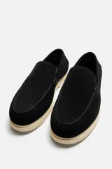 Mocasín casual de hombre color negro, con capellada de cuero serraje, corte liso con detalle de bordón y suela color crema.