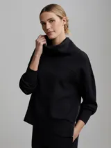 Buzo negro de corte oversize con cuello alto, mangas abullonadas, cierre lateral y hombros caídos.