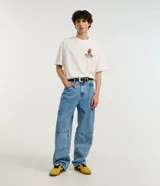 Remera color crudo de corte boxy, con cuello redondo y mangas cortas. Estampado trasero con un gallo con gafas y zapatillas, la palabra 'Rooster' y la frase 'Stay Cocky'.