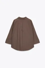 Camisa marrón de popelina con cuello solapa, escote en pico, cierre frontal con botones y mangas anchas con puños.
