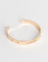 Brazalete dorado de metal con la palabra "Lovely" calada y pequeños corazones troquelados.