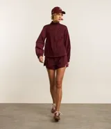 Campera deportiva rompevientos color bordó, con cuello alto, cierre frontal con cremallera, puños elastizados y recortes con hilo reflectante.