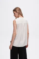 Blusa viscosa color negro, corte evasé, sin mangas, con cuello a la base y botón en la parte superior.