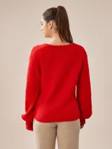 Buzo de tejido de punto rojo, con escote en V cruzado tipo wrap y mangas largas abullonadas con puños ajustados.