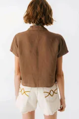 Camisa celeste de lino con cuello clásico, mangas cortas, corte crop y lazos en el frente.