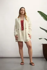 Blazer celeste de lino con solapas de muesca, cierre cruzado con botones, bolsillos delanteros con solapa y corte holgado.