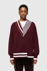 Sweater de punto color borgoña con cuello en V, diseño asimétrico con rayas en contraste y detalle de tejido texturizado en un lateral.