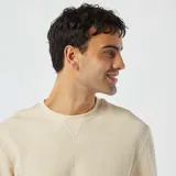 Sweater color crema de punto de piqué con cuello redondo y mangas largas.