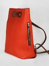 Mochila de cuero graneado color verde oscuro con detalles en cuero color marrón. Cuenta con un bolsillo exterior y un bolsillo interior con cierre, además de un compartimento interno para celular.