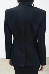 Blazer negro con cuello solapa de muescas y manga larga. Tiene falsos bolsillos de vivo en el delantero, forro interior a tono y cierre frontal cruzado con botón a presión.