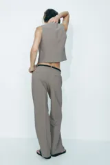 Pantalón de tiro alto con estampado a cuadros en tonos beige y marrón, con bolsillos delanteros y falsos bolsillos traseros. Incluye cinturón marrón con hebilla metálica.