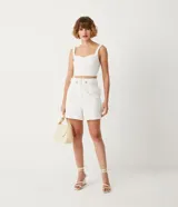 Blusa cropped blanca de lino con escote en V y tirantes trenzados.
