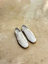 Zapatillas bajas de cuero negro con cordones y suela de goma color caramelo.