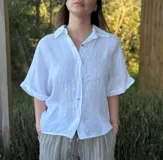 Camisa marrón de lino con botones blancos, corte holgado y mangas cortas.