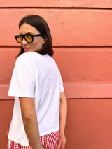 Remera blanca de algodón con estampa azul de una mesa con una botella de vino, una copa y un plato con comida.