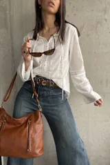 Blusa blanca de manga larga con detalles de encaje en el frente, mangas y cuello.