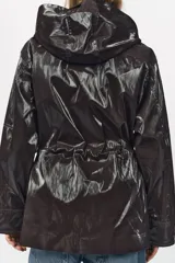 Parka marrón brillante con cuello alto y capucha oculta con cremallera metálica. Manga larga ajustable con cinta y botones a presión. Bolsillos delanteros con cremallera metálica. Cintura ajustable. Cierre frontal con cremallera y botones a presión.