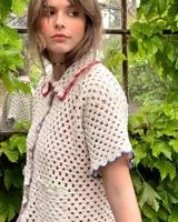 Saco tejido a crochet color crudo con detalles de terminación en rosa, verde y celeste.