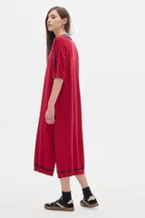 Vestido midi tejido color rojo con cuello polo a rayas azul marino y blanco, manga corta con detalle de rayas azul marino y aberturas laterales.