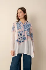 Túnica azul con bordados florales, cuello camisero y botones forrados.