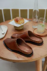 Mules de cuero negro con punta cuadrada y detalle de tachas plateadas en el borde superior.