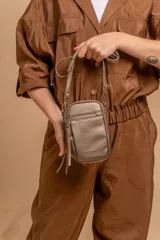 Bandolera compacta de símil cuero color rojo, con correa regulable y desmontable. Posee apertura superior, bolsillo frontal con cierre y bolsillo trasero abierto.