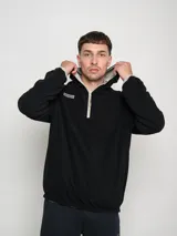 Campera canguro deportiva negra con capucha y medio cierre frontal. Detalles en azul en el logo, interior de la capucha y ribete de los bolsillos.