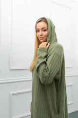 Vestido largo de tejido acanalado color verde oliva, con capucha, escote en V y mangas largas. Presenta bolsillos laterales y aberturas en los bajos.
