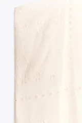 Top blanco de algodón con tirantes finos y bordados combinados a tono.