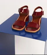 Sandalias de cuero color cereza, con tira ancha sobre los dedos, tira con hebilla al tobillo y taco cuadrado de madera.