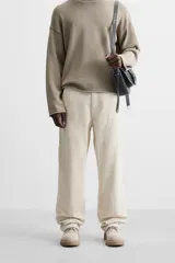 Pantalón de pana color crema, corte relaxed fit, con bolsillos frontales, bolsillos de parche en la parte trasera, bolsillos laterales en las piernas, trabilla multifunción y cierre con cremallera y botón.