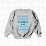 Buzo gris de corte clásico con cuello redondo y mangas largas. Estampado frontal con la frase "TU DISEÑO ACÁ" repetida varias veces en color azul.