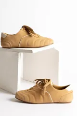 Zapatillas acordonadas color beige con detalles en blanco.