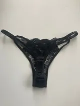 Bombacha tipo tanga de encaje negro con tiras regulables en los laterales.