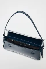 Bolso de hombro alargado azul marino acharolado con bordes en contraste blanco, asa corta, bolsillo interior con cremallera y cierre con solapa y botón imantado.