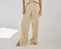 Pantalón de lino color beige, de corte clásico y pierna recta con tajos laterales en el ruedo. Tiene cintura elastizada.