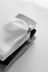 Pack de tres pares de medias de caña alta, una blanca, una gris y una negra, con logo en el tobillo.